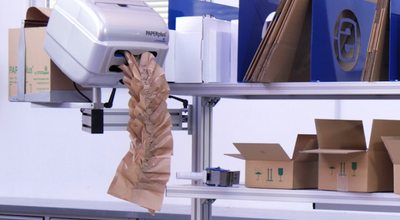 
				The image shows a packaging station equipped with a paper cushioning machine. 