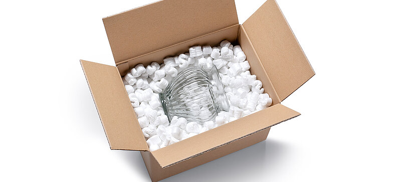 Ein Karton mit einer Glas Vase und weißen S-förmigen Verpackungschips